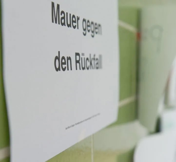 Text auf einem Zettel an der Tür: "Mauer gegen den Rückfall"