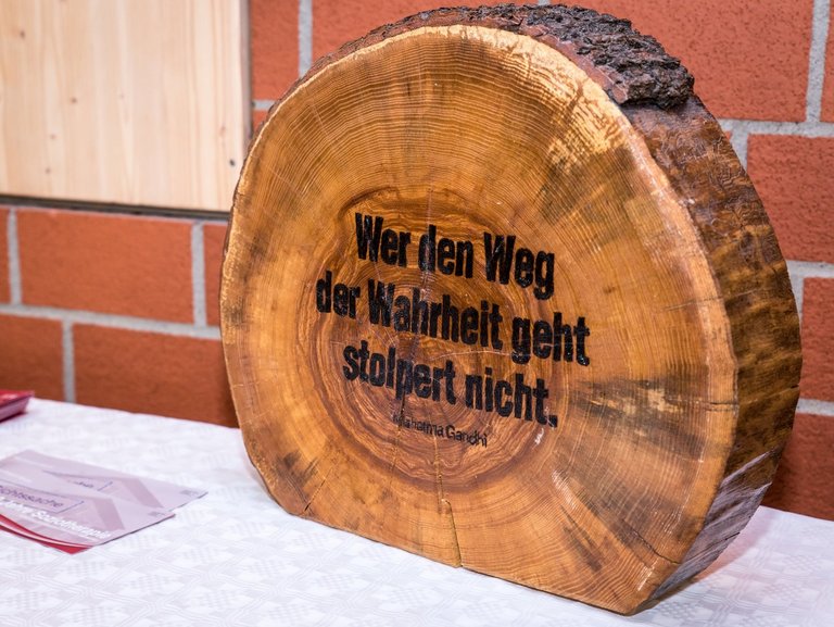 Holzstamm-Scheibe mit eingebranntem Spruch: "Wer den Weg der Wahrheit geht stolpert nicht - Mahetma Gandhi"