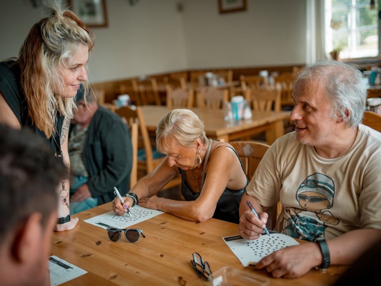 Eine freundliche Mitarbeiterin mit Brille und dunklen Haaren ist im Gespräch mit einem jungen Mann