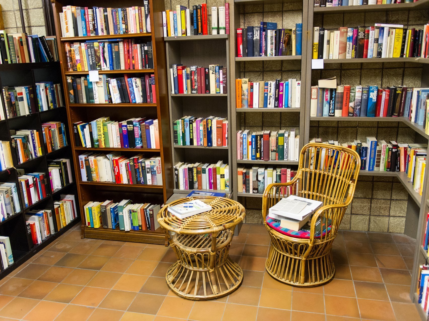 Bücherregale voller Bücher. Davor ein kleiner Tisch und ein Stuhl.